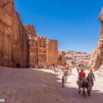 A newly discovered ancient tomb in Petra, Jordan, carved into rose-red rock cliffs, showcasing intricate Nabataean architecture and revealing recent archaeological findings.