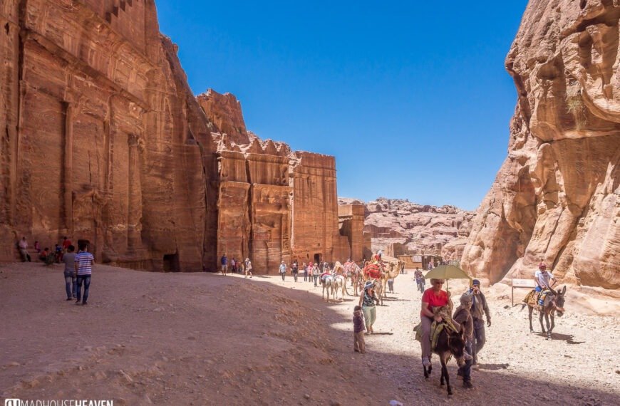 A newly discovered ancient tomb in Petra, Jordan, carved into rose-red rock cliffs, showcasing intricate Nabataean architecture and revealing recent archaeological findings.